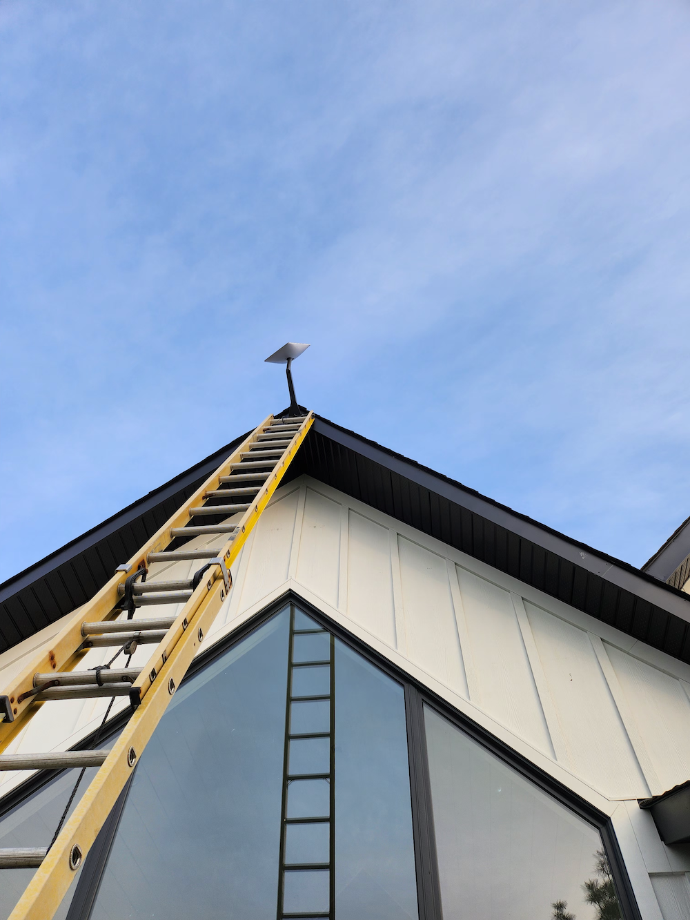 j-arm starlink installation at the top of a tall peaked roof