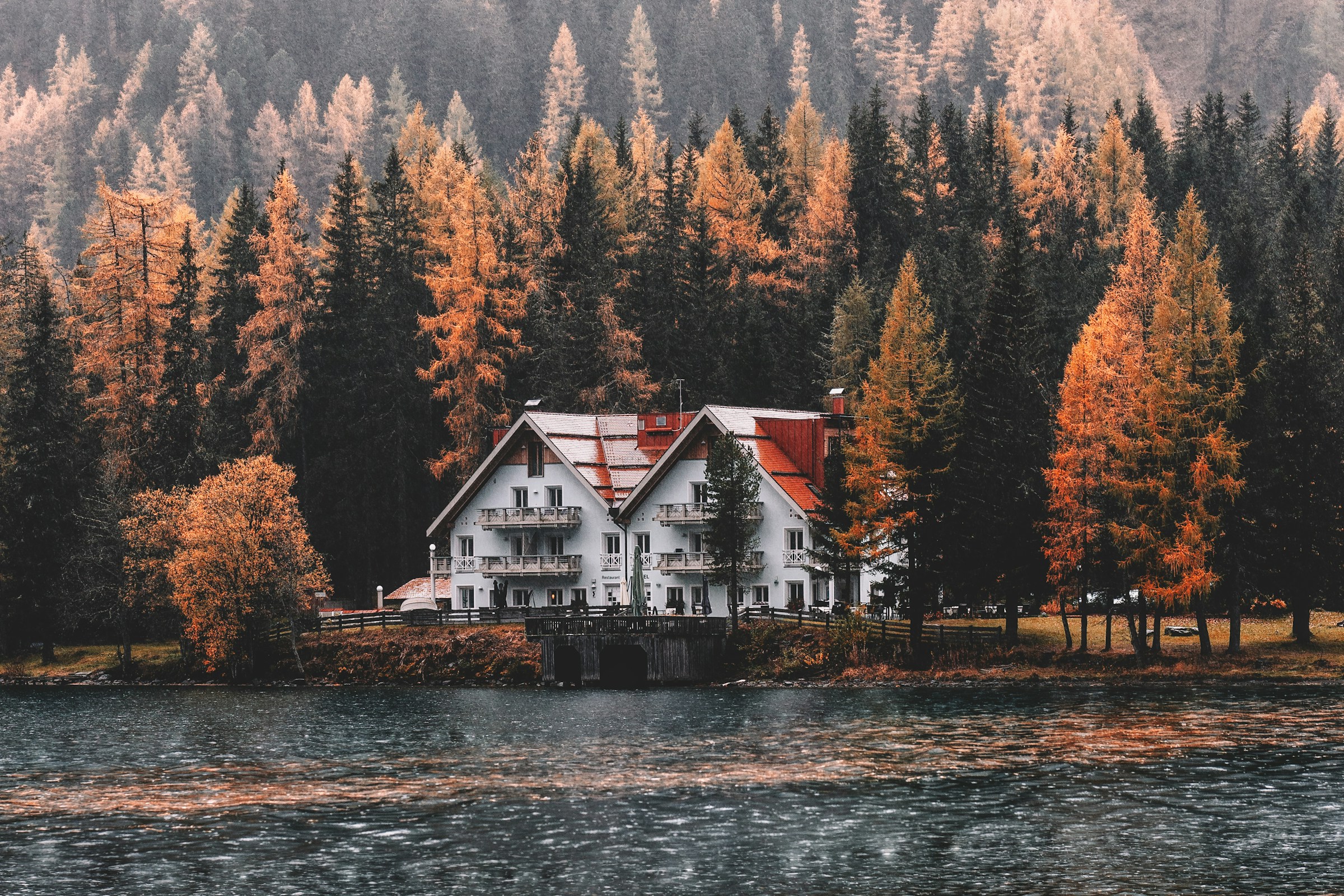 red-roofed mansion on a lake of fall trees